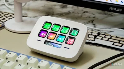 A white Stream Deck device with two rows of four buttons, and beneath them, a short LED display showing the time as 12:59pm.