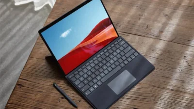 A laptop standing open on top of a wooden surface. The screen shows a red desert scene with blue sky.