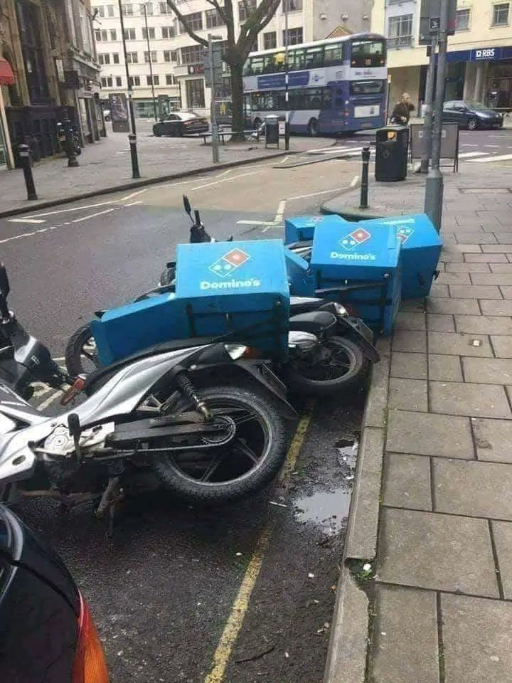 a line of dominos pizza delivery mopeds that have fallen over like dominos