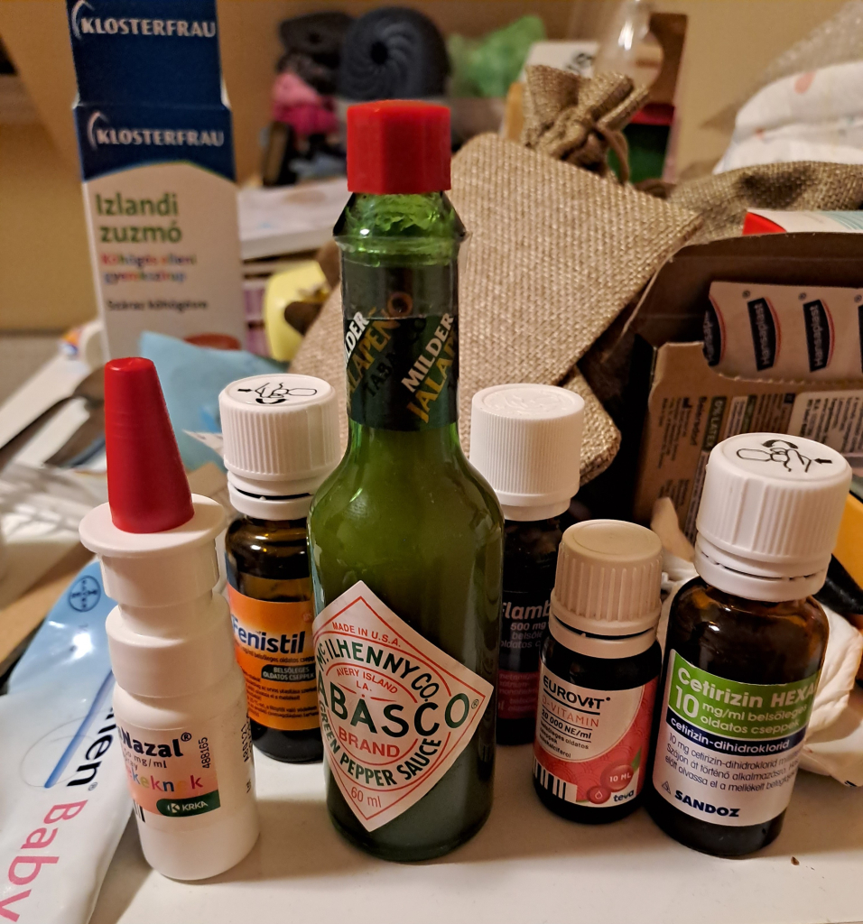 A photo of various nasal sprays, syrups, and vitamin drops, and one bottle of green tabasco 