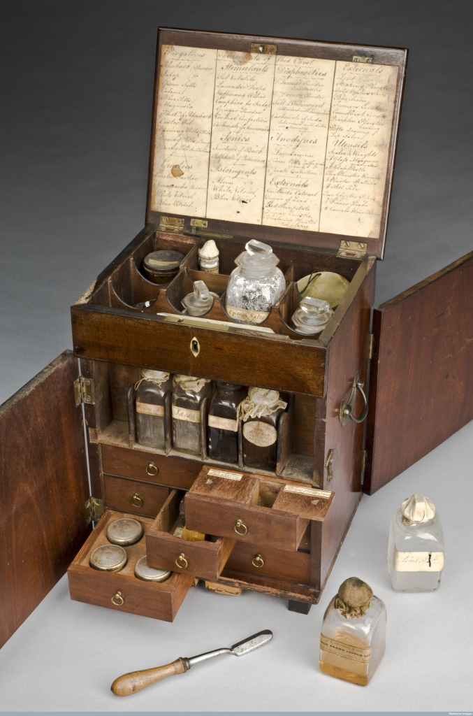 A photo of the Victorian medicine chest. It is open at the front to reveal glass bottles inside and various drawers containing instruments. 