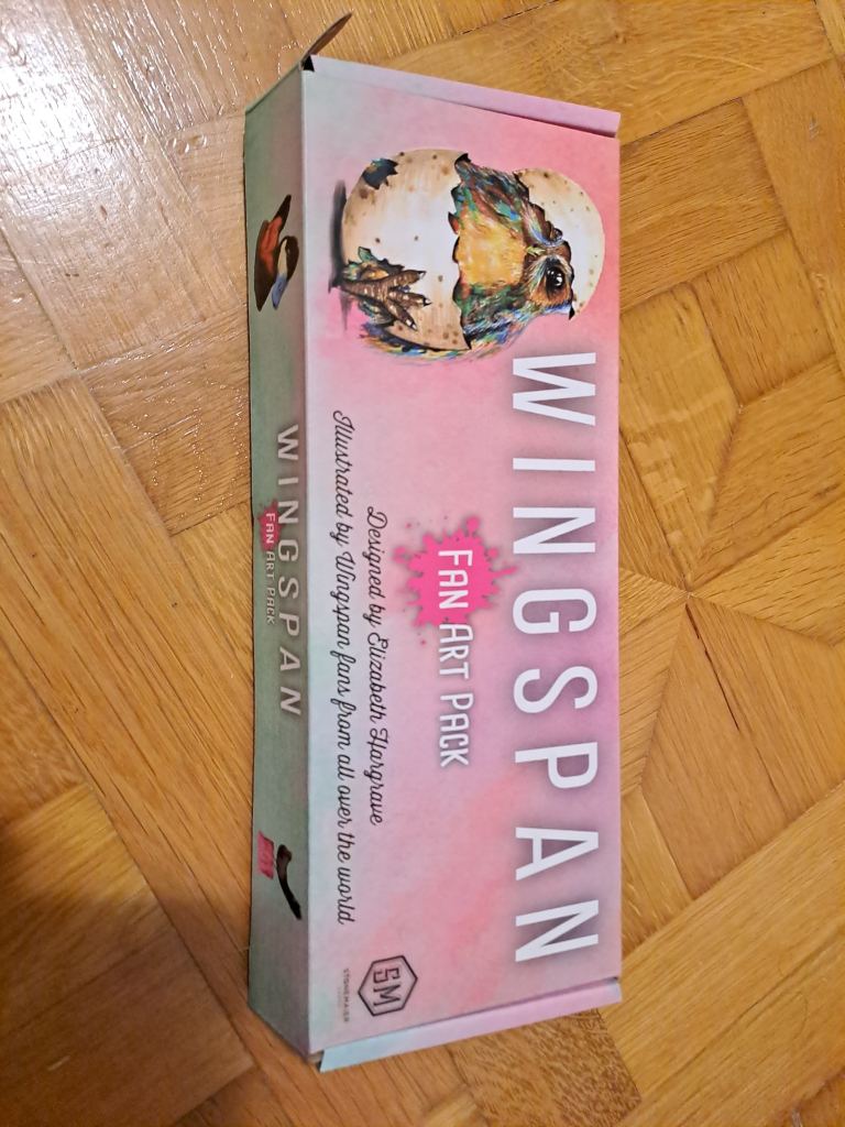 Pink and teal Wingspan board game box, with the image of a colorful owlet hatching from an egg. The box says Wingspan - Fan Art Pack 