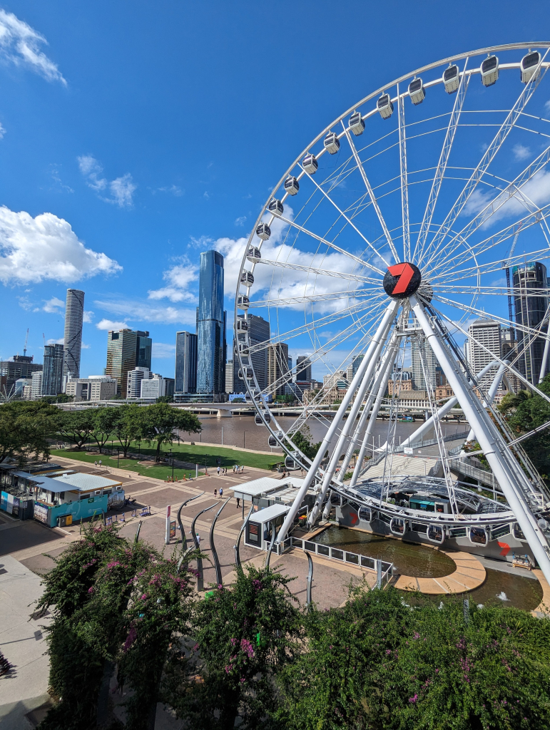 South bank. blue sky, green grass, brown river. The Channel 7 wheel in the foreground