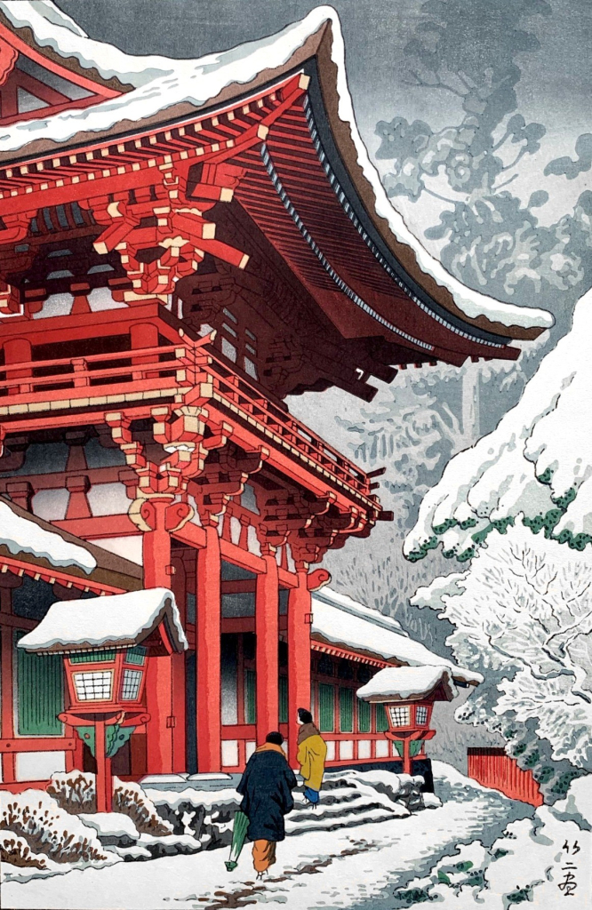 A view of the grounds at Kyoto's Kamigamo Jinja on a snowy winter's day. Walking separately, two visitors in warm-looking coats approach the Honden Sanctuary along a rough path broken in the shallow layer of snow lying across the ground. The Honden Sanctuary stands to the left; snow sticks to the sweeping curved rooftops of the building, contrasting with the intense red of the exterior. On the right, snow covers the ground and clogs the branches of trees. Beyond, faint shadowy shapes of more trees blend in with an overcast sky