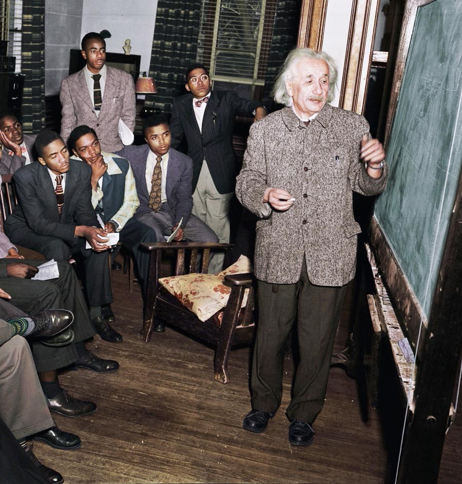 Albert Einstein stands in front of a blackboard in a room full of Black men at Lincoln university, teaching a graduate class in physics.