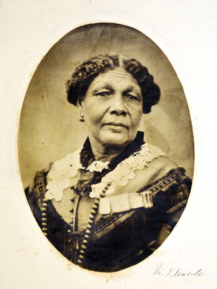 Sepia portrait photo of Mrs Seacole, wearing a 19th century dress with lace collar and bead necklace, her hair pinned up. 