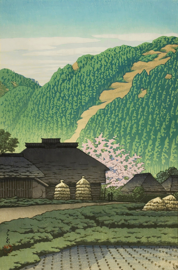 A view of a farm in the mountains of Japan on a bright spring day. In the foreground, flooded rice paddies have been prepared with new plants, making a regular pattern of evenly-spaced dots across the water. Beyond, a rough road leads toward a traditional Japanese thatched-roof farmhouse and its various outbuildings. A cherry tree standing near the house is in full bloom, its branches loaded with pink blossoms and reaching up higher than the roof of the house. Further on, low nearby mountains are crowded with healthy-looking pine trees, while above, a few hazy clouds hug the mountaintops beneath a bright blue sky