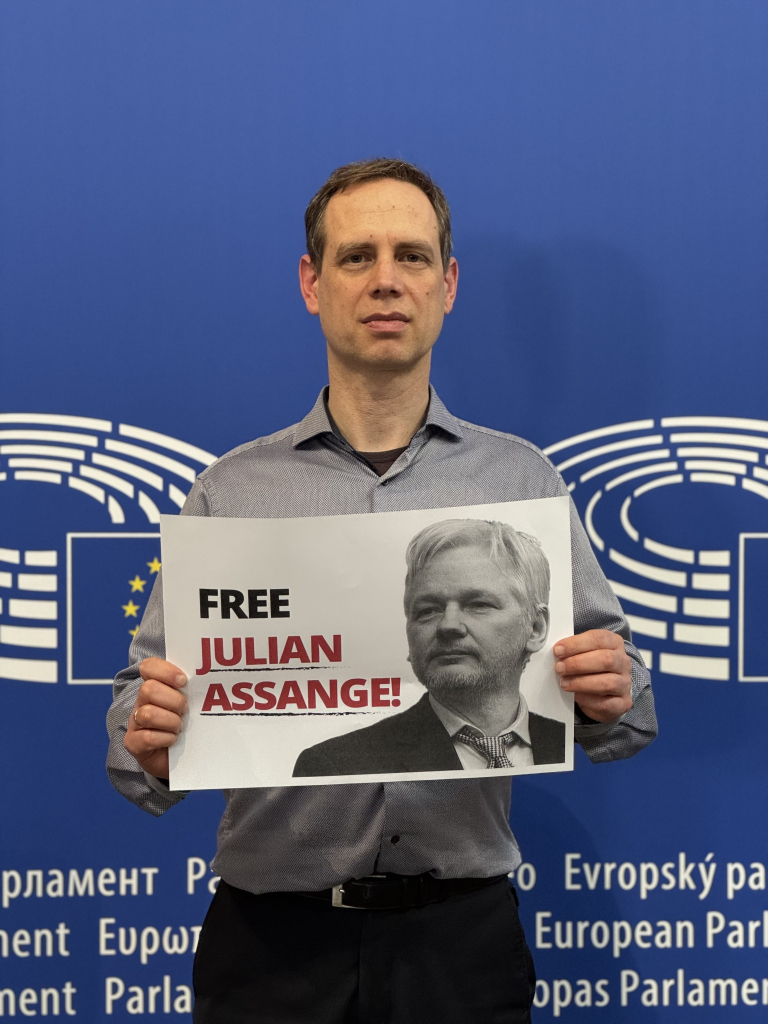 Patrick Breyer hält ein Schild "Free Julian Assange"