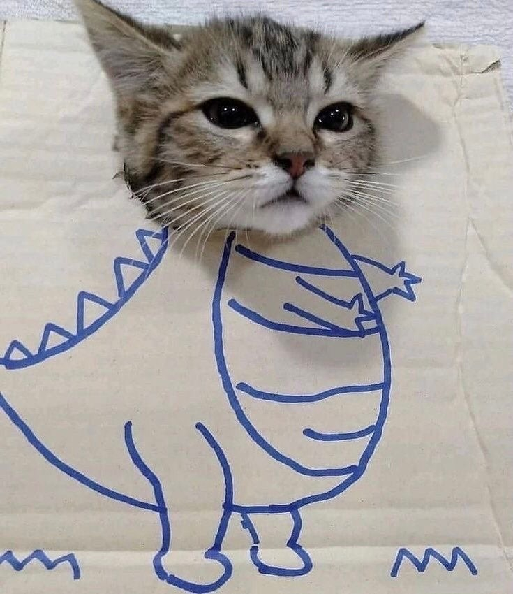 grey tabby cat's head, stuck through a piece of cardboard with a godzilla-like body drawn below