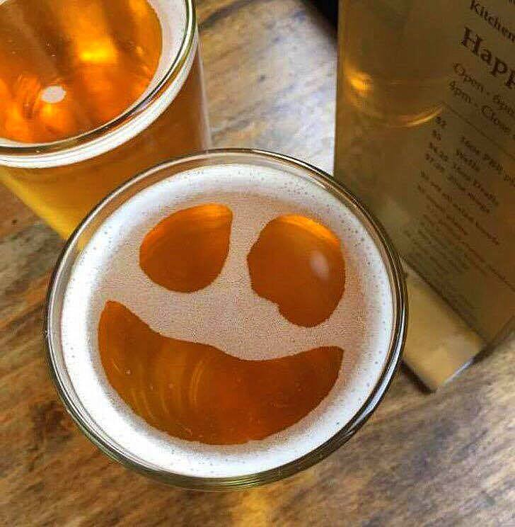 bubbles on the top of a beer glass that look like a big happy face