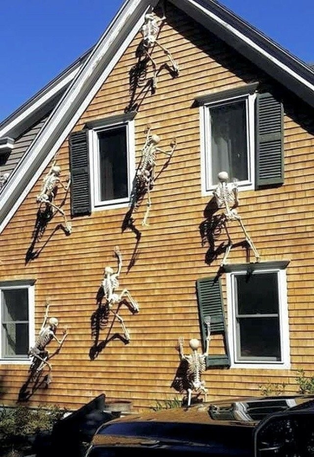 skeletons climbing up the side of a house