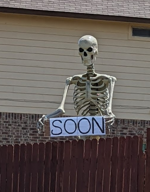 giant skeleton holding a sign that says "soon"