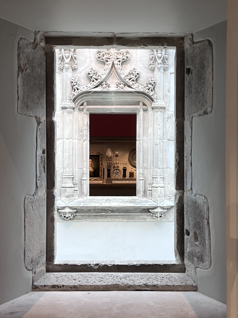 A view through a medieval window at the Burrell collection to a mother and looking into one go the galleries