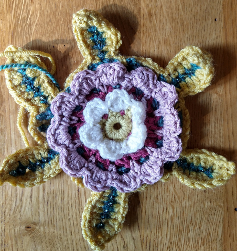 Legacy motif crochet flower in pinks yellow and green, the  six leaves are decorated with beads 