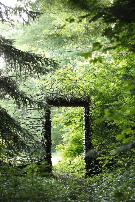 Photo: Passage, 2007 by installation artist Cornelia Konrads 
In a forest, a doorway has been woven out of branches and place in the gap between trees to suggest a portal to another place....