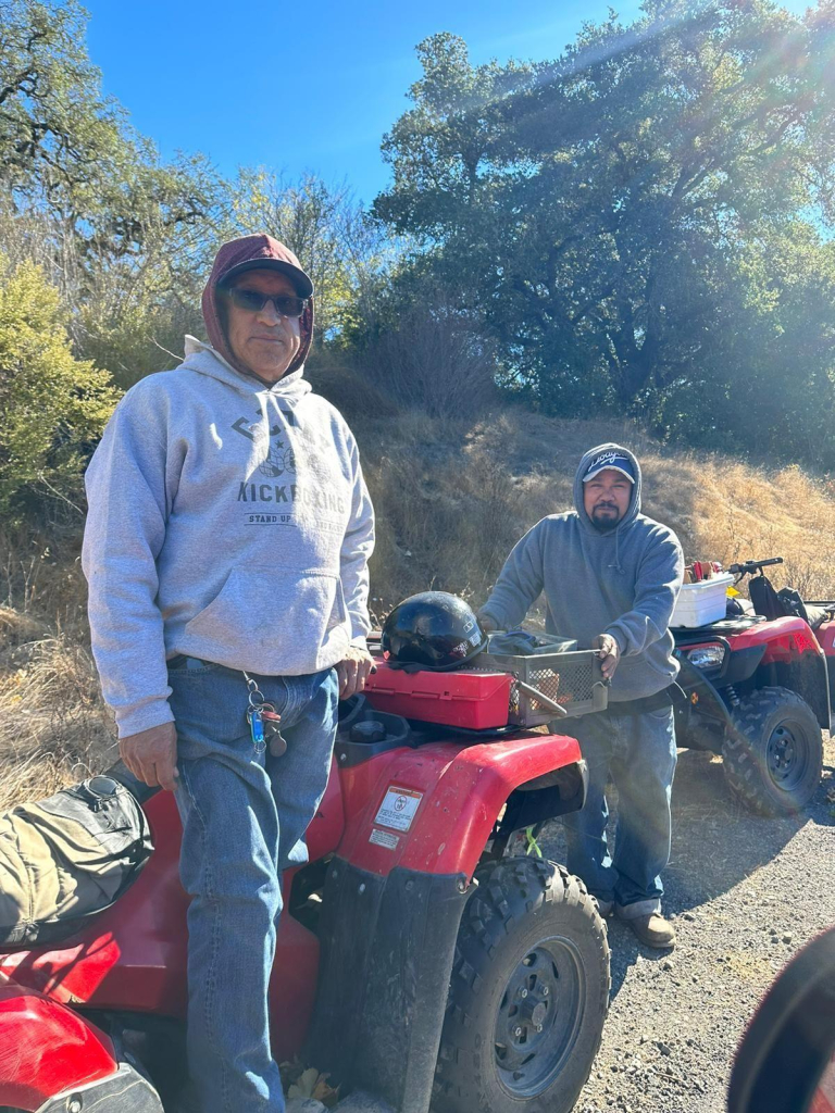 Two farm workers standing in front of a 4 by 4 they are using to deliver essential equipment to other workers