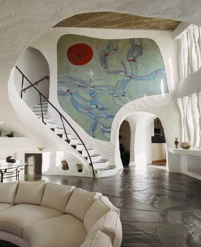 Domestic interior with curving white walls, curving steps, and a large abstract mosaic wall decoration