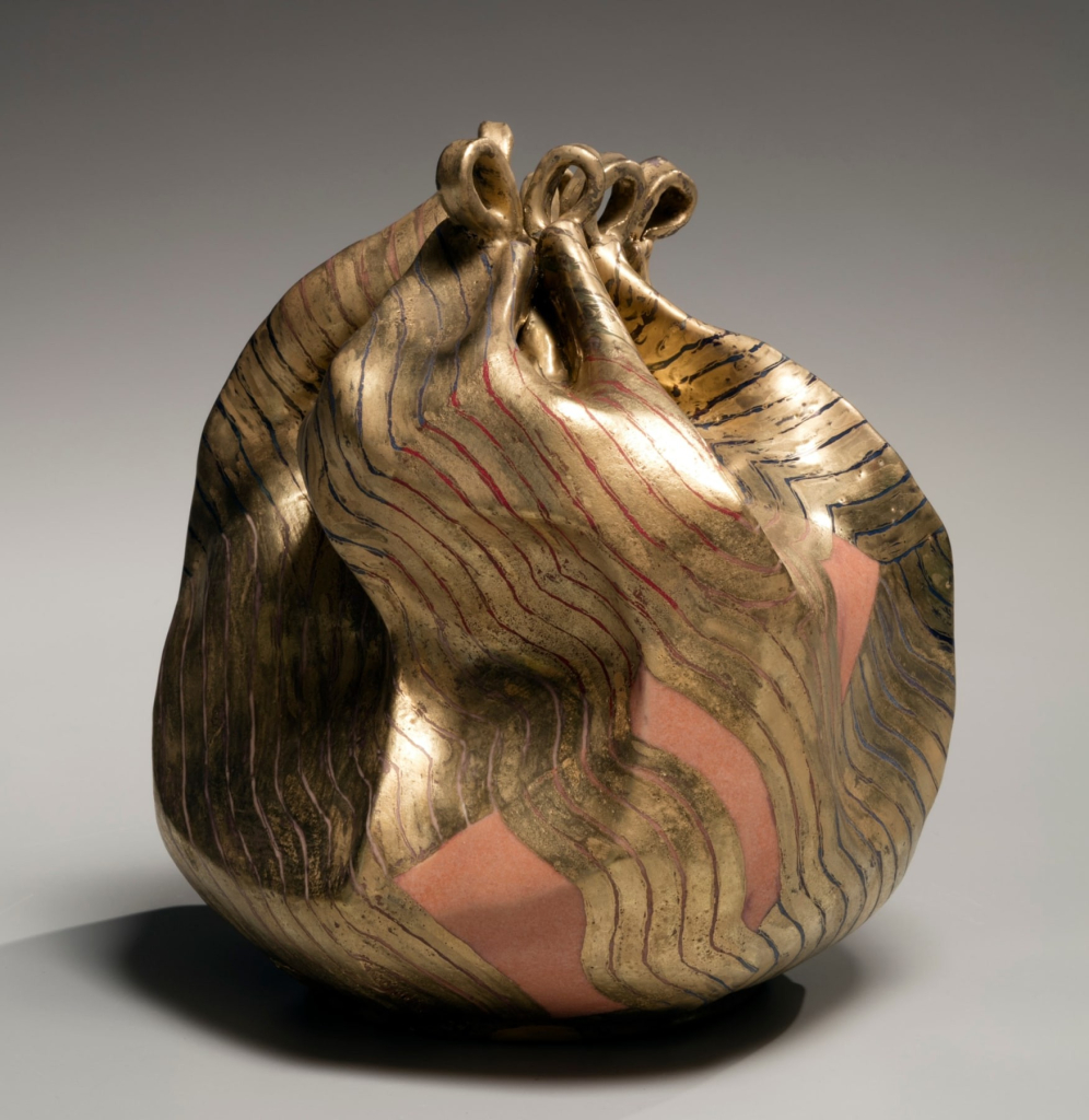 Ceramic sculpture resembling fabric gathered up into a ball or sack, covered in gold stripes