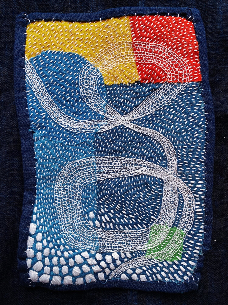 Abstract embroidery with swirling white threads over patches of blue, yellow, and red