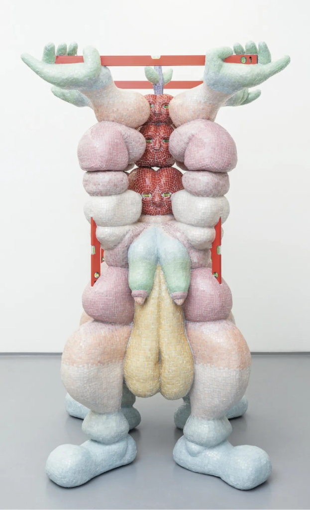 Abstract sculpture decorated with pastel mosaic tile, made of symmetrical biomorphic forms resembling a bulbous cartoon figure lifting a metal bar