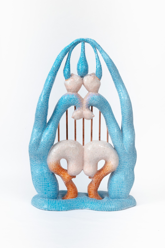 Abstract sculpture decorated with blue, cream, and orange mosaic tile, made of symmetrical biomorphic forms