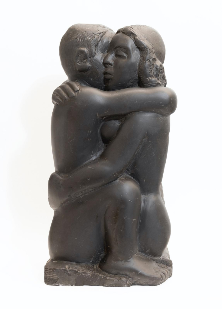 Black stone sculpture of two figures embracing, their bodies seeming to merge in one block