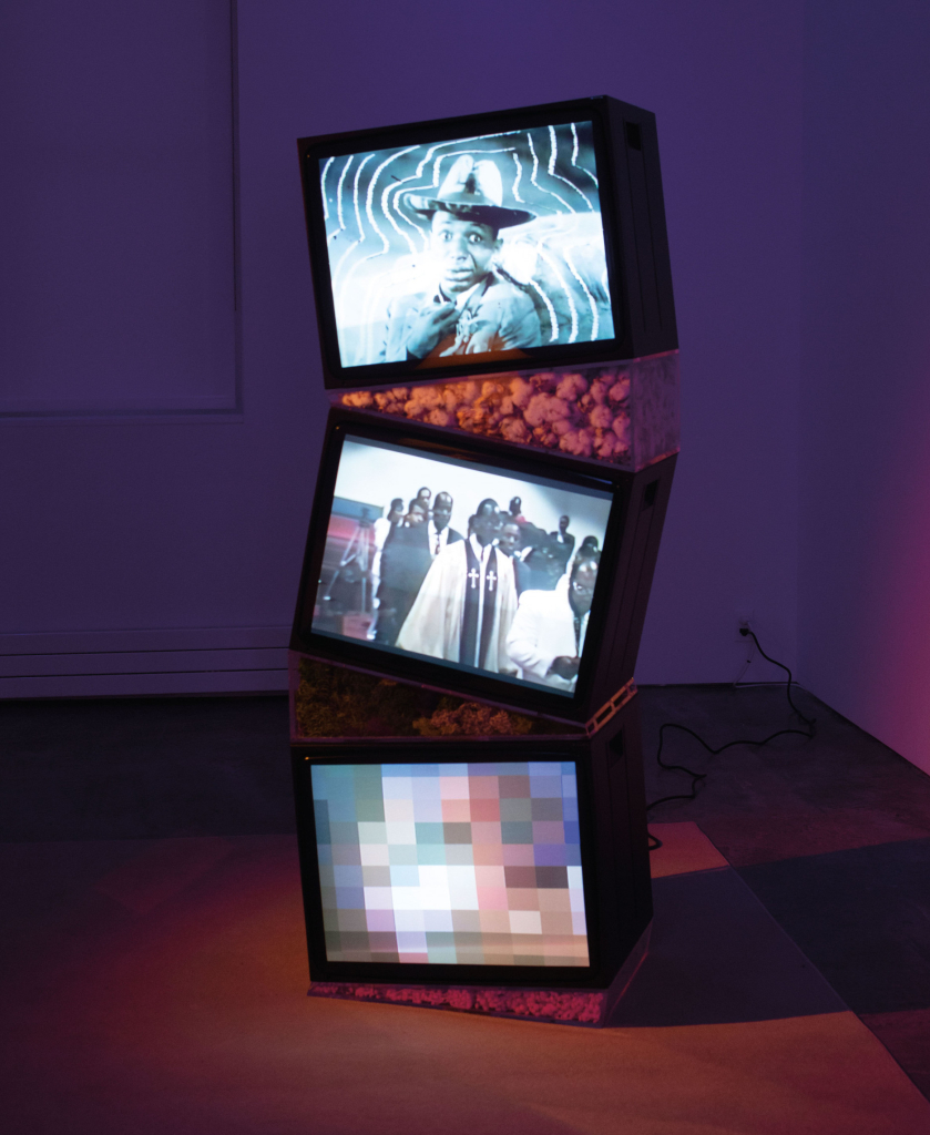 Sculpture of a triple tv arranged in a slightly askew tower, each with different images of Black folks on screen