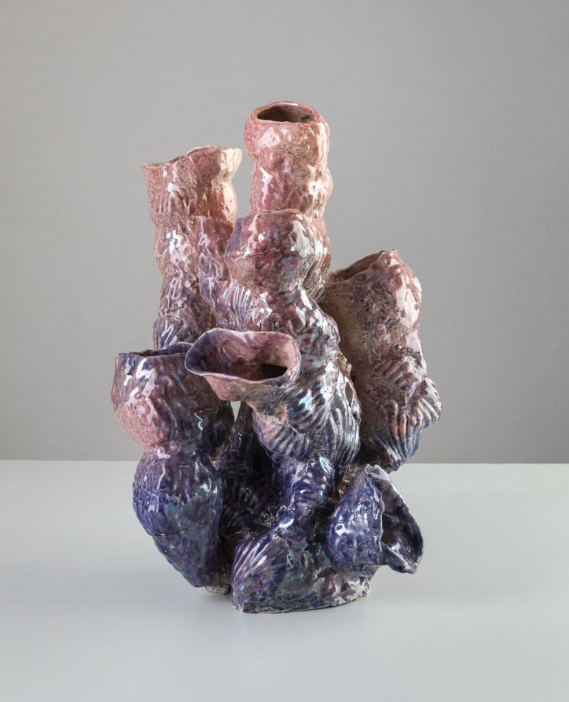 Abstract sculpture resembling a type of coral, with several oval openings and a textured, pink and purple gradient exterior