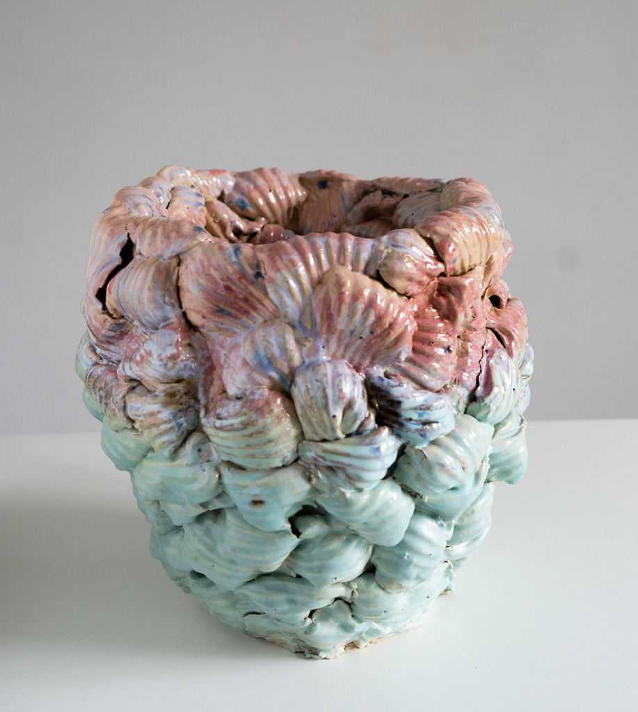 Abstract sculpture in a rounded vessel shape with a bumpy, lined texture and pink and green gradient exterior