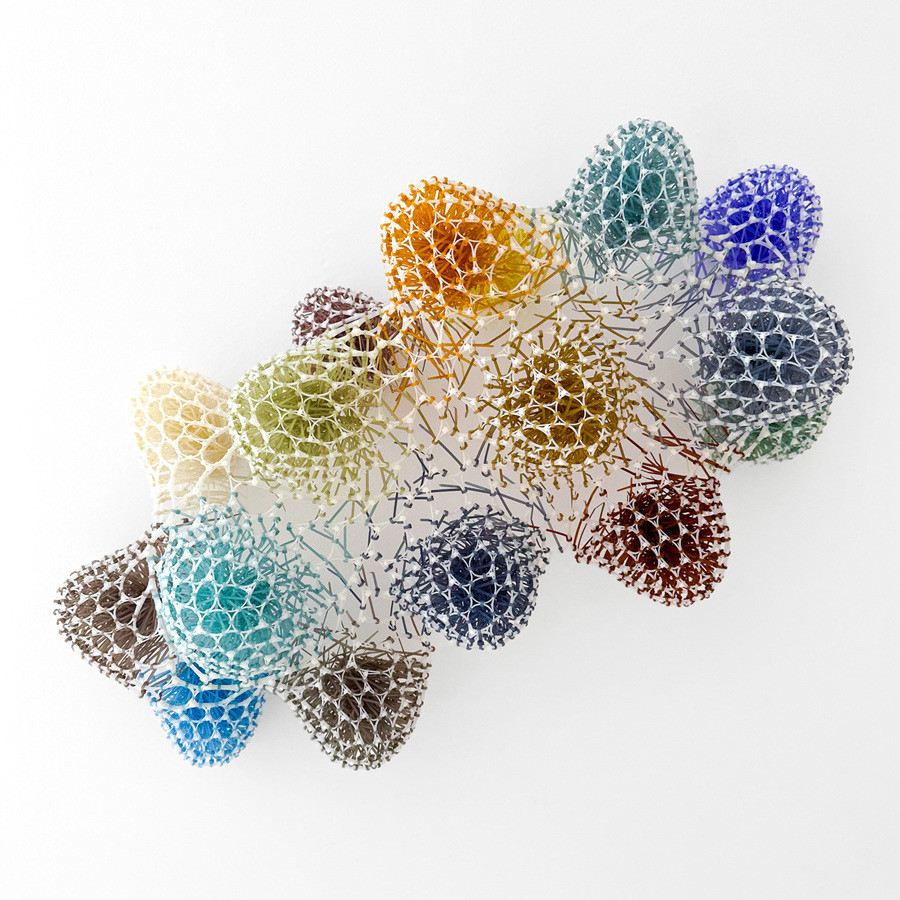 Sculpture of colorful round forms connected by white interlaced plastic