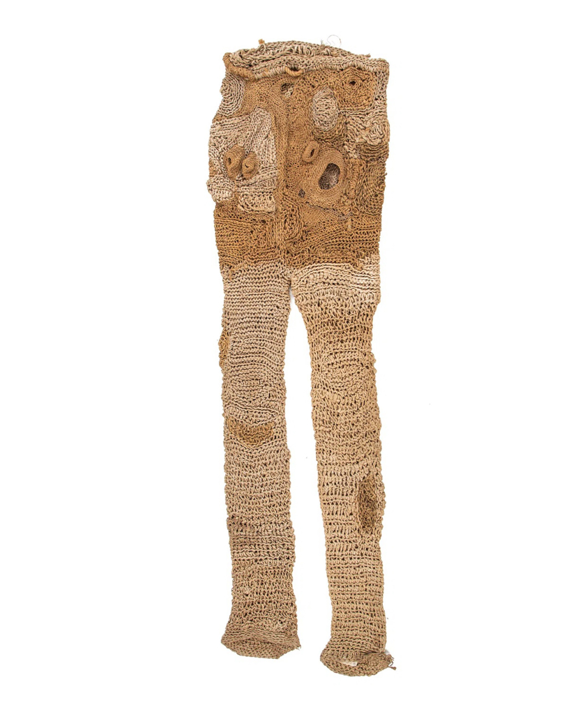 Hanging light brown fiber sculpture of a long pair of pants with textured bumps and holes