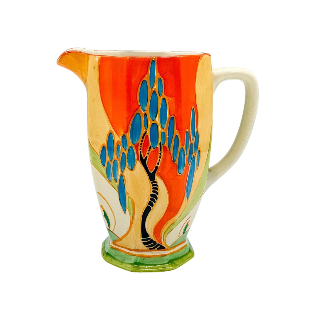 Ceramic pitcher with a brightly colored design of a tree with blue circle flowers and orange background