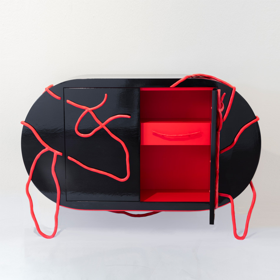 Oval cabinet with red shelving interior and a black exterior covered with curving red lines