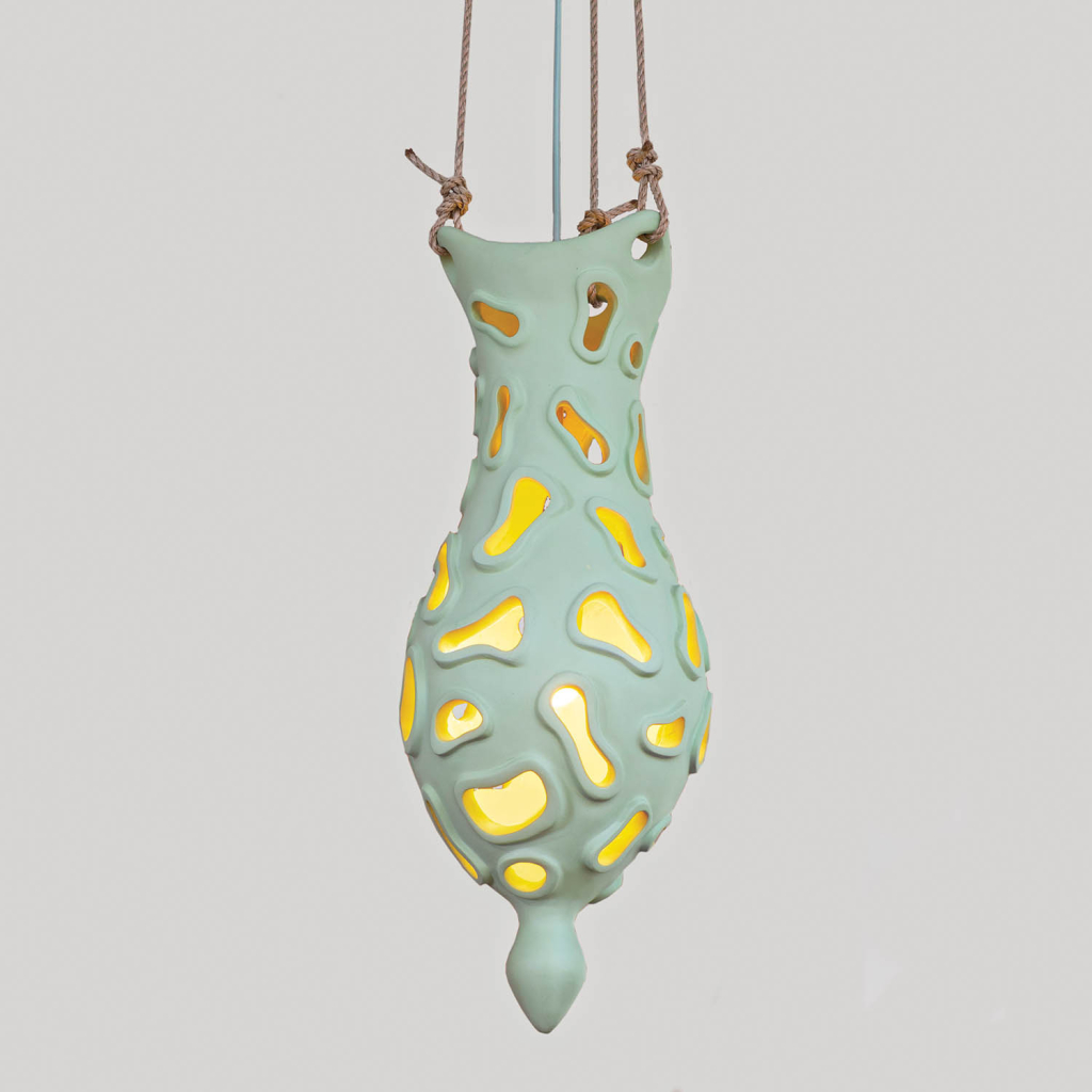 Hanging, oval-shaped lamp in pale green with wonky openings revealing a soft yellow light