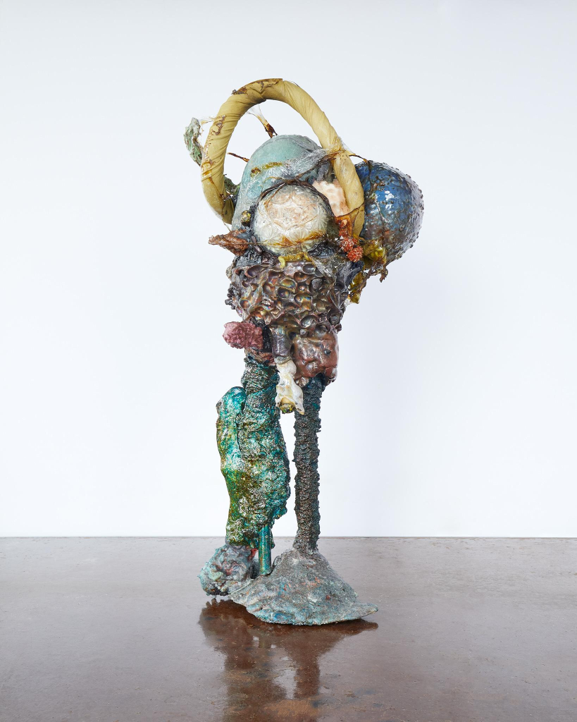 Sculpture of a standing abstract figure made up of various found objects and materials