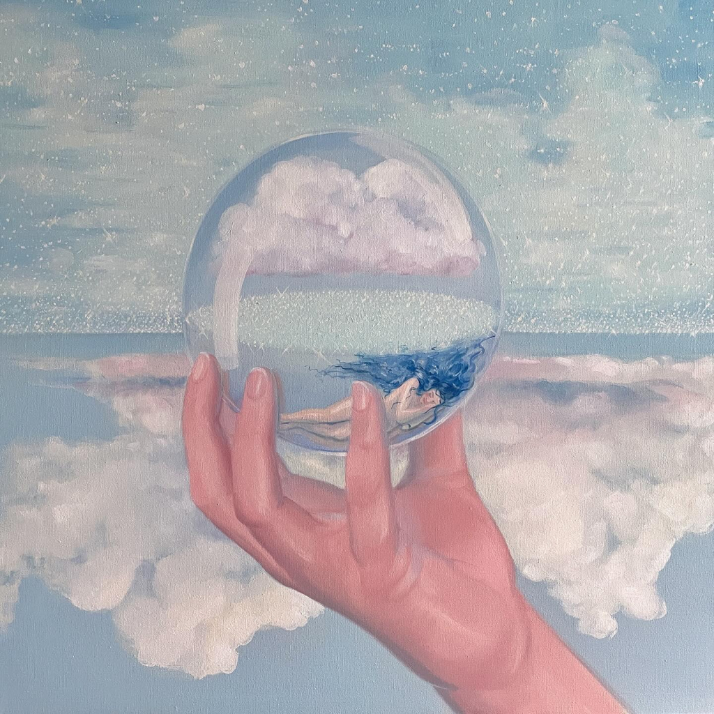 Painting of a white hand holding up a round glass orb, within is pale sleeping figure with long blue hair and a cloud. The background is seemingly upside down seascape with clouds on the bottom and sparkling water above