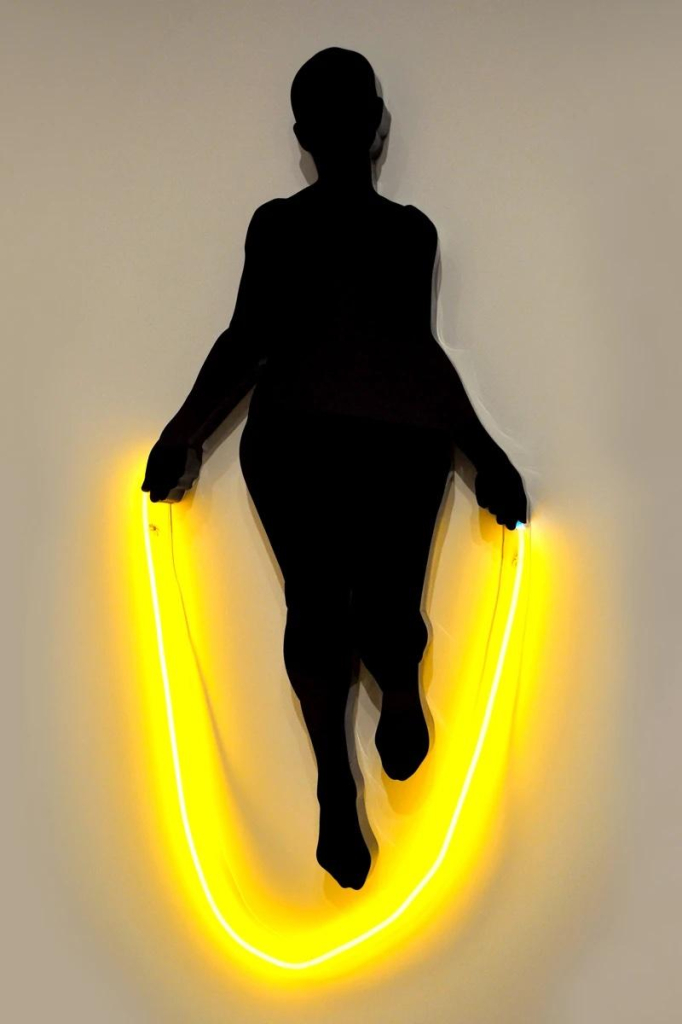 Black silhouette of a figure jumping rope with a neon yellow light strip