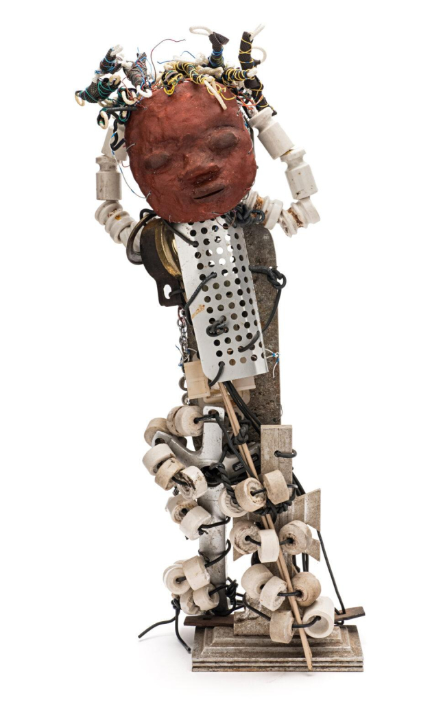 Sculptural figure made up of metal parts, beads, and electrical wires, with a red clay face