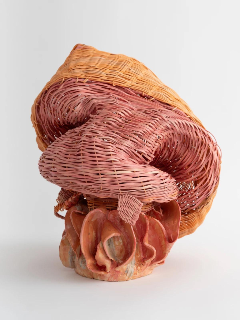 Basket weave sculpture in soft pink and orange cream, with a ceramic base of organic curves