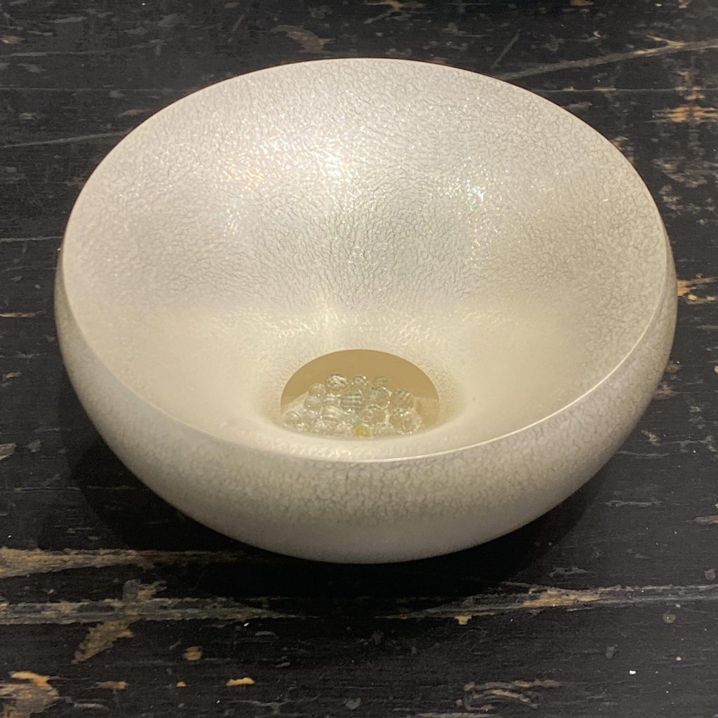 Smooth round bowl with a small central hole showing glass beads inside and a white craquelure surface texture