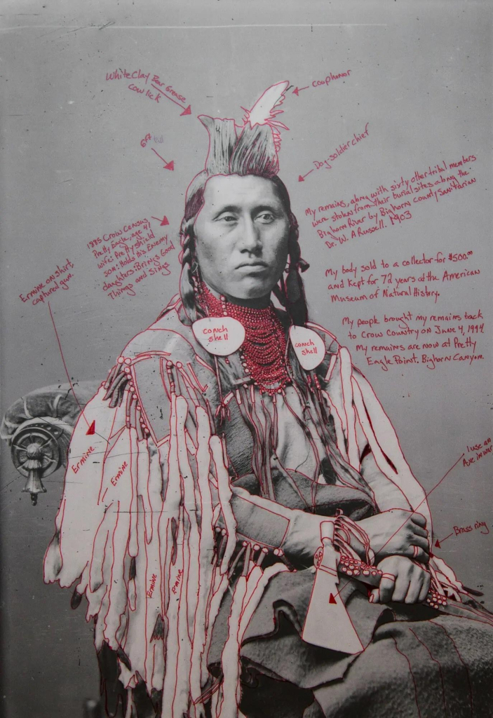 Black and white photo portrait of a Crow chief, with notes in red pen added identifying different aspects of his clothing and additional symbols, along with some hypothetical observations