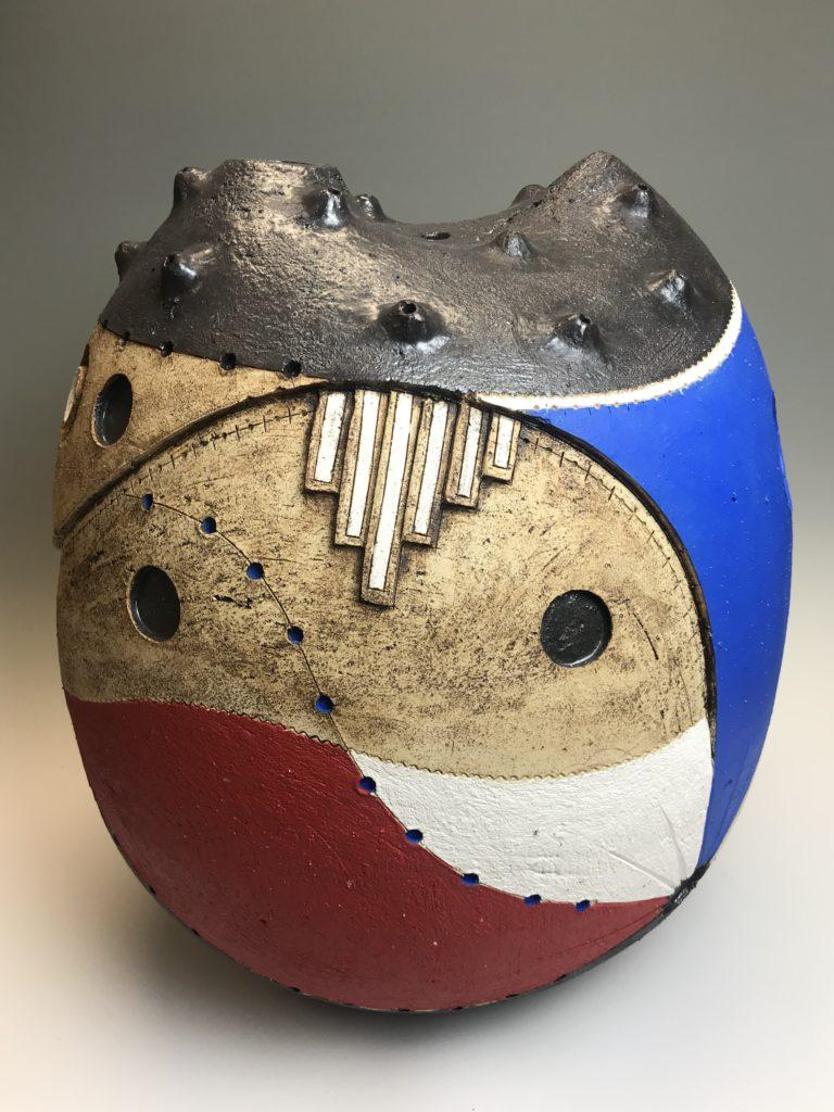 Ceramic form with a rounded base and pointed metal top, decorated with swirling abstract shapes in red, blue, and white