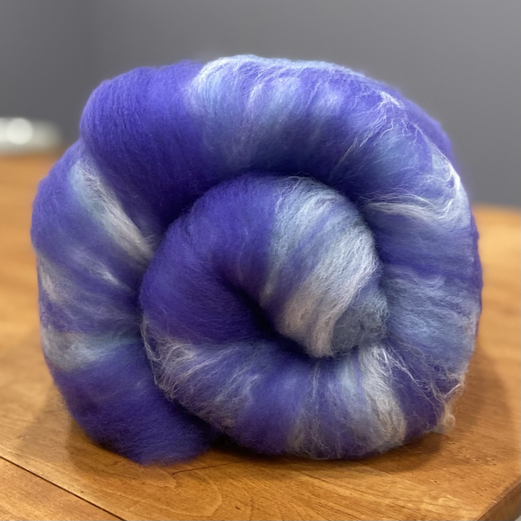 A rolled up purple, blue and white wool batt 