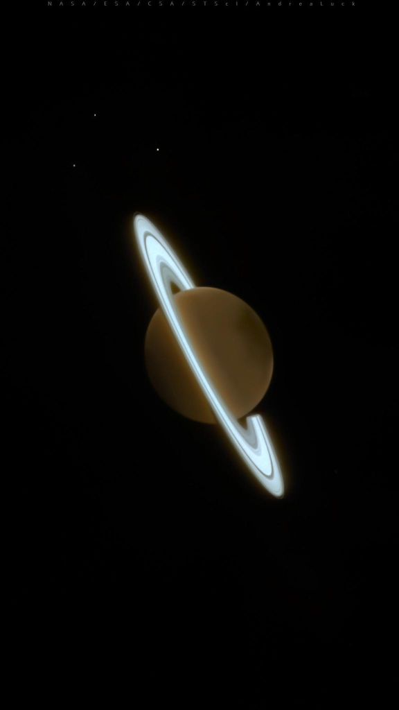 Image of Saturn and some of its moons, captured by the James Webb Space Telescope’s NIRCam instrument on June 25, 2023. The planet is a dark orange while the rings are a bright, pale blue. The planet is tilted from upper left to lower right, with the three moons at the top.