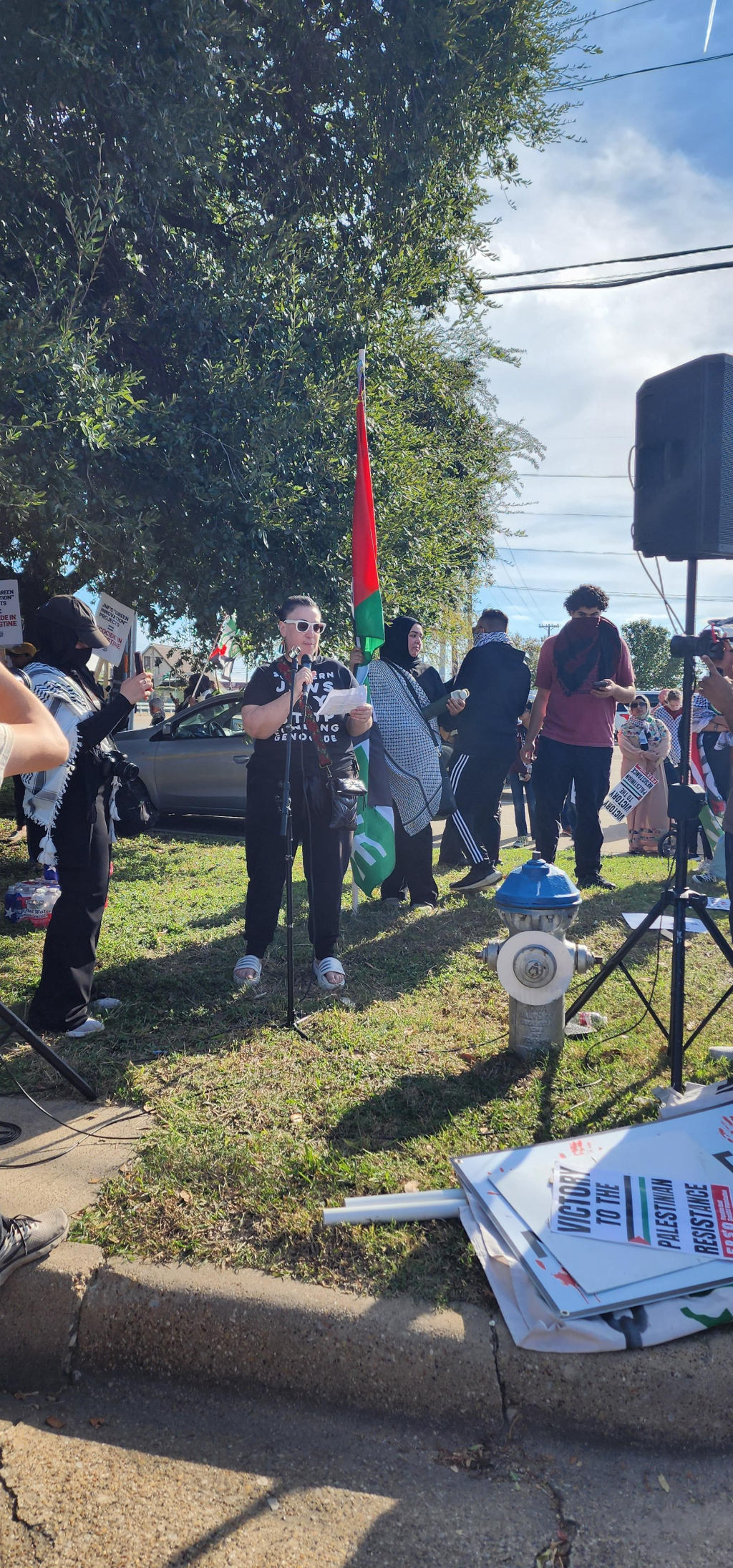 A woman speaks in a Not In Our Name JVP shirt among a crowd of protesters 