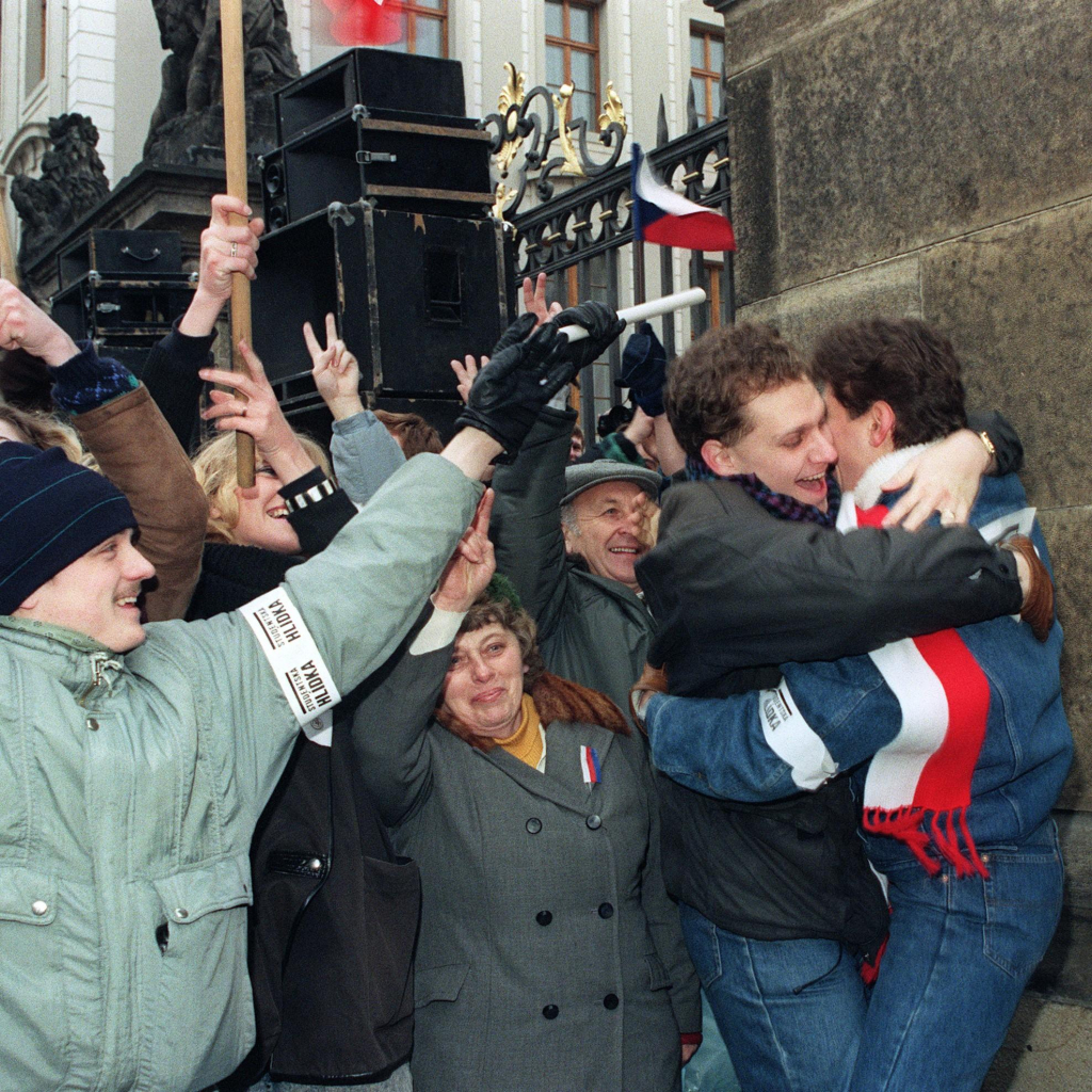 People celebrating at the Prague Hradcany Castle in support of Vaclav Havel, following his election as Czechoslovakia's first non-communist president since 1948. They wave flags and make the victory sign with their hands. 