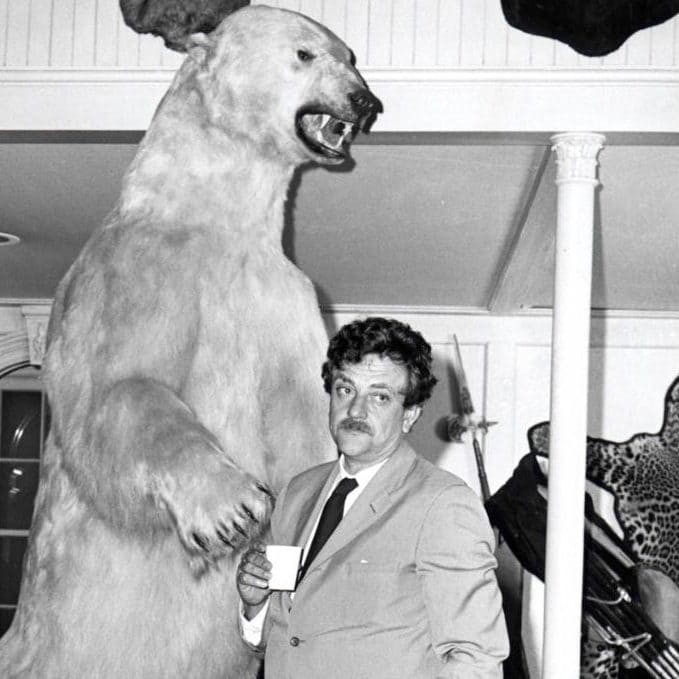 Kurt Vonnegut having a coffee, standing next to a stuffed polar bear standing on its hind legs