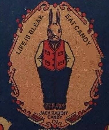 Strange advertising image.  On a denim blue background, inside a sand-coloured oval surrounded by candy canes and sweets, a colour pencil sketch of a rabbit is looking out from the frame.  He's wearing blue trousers and a red waistcoat.  Text reads:
LIFE IS BLEAK
EAT CANDY
JACK RABBIT CANDY CO