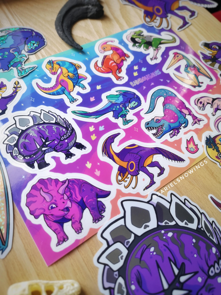 A picture of a sticker sheet of 11 diffrrent dinosaurs, each with the colour of a different pride flag. 