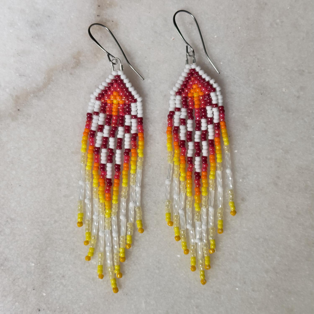 A pair of white, yellow, orange, and red beaded fringe earrings on a marble background